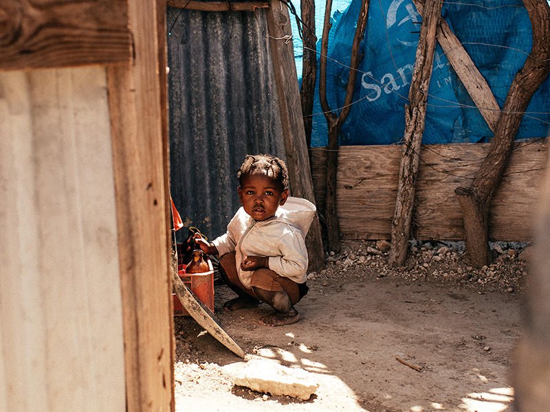 A child standing outside a home in a rural community